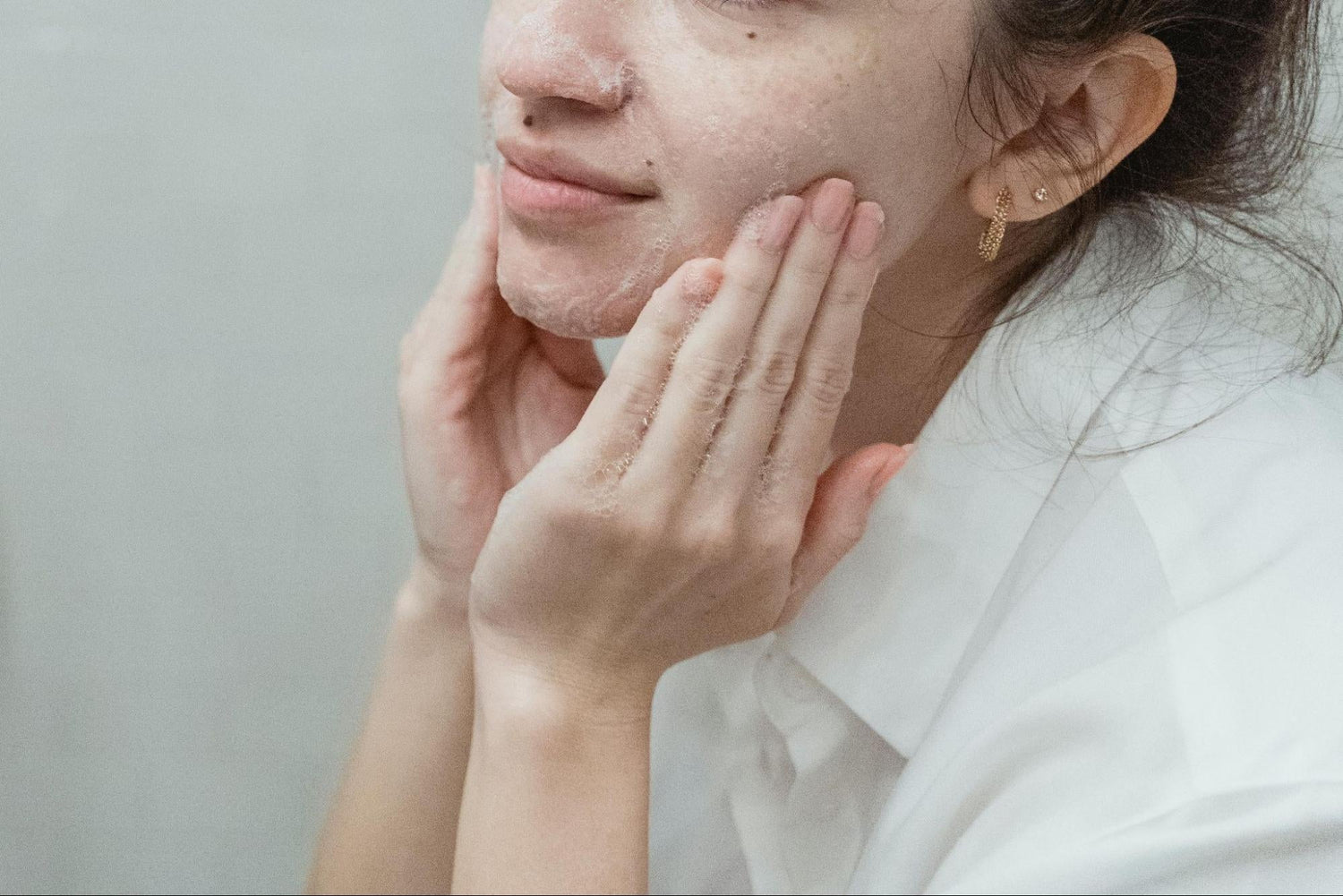 A woman lathers cleanser on her face.